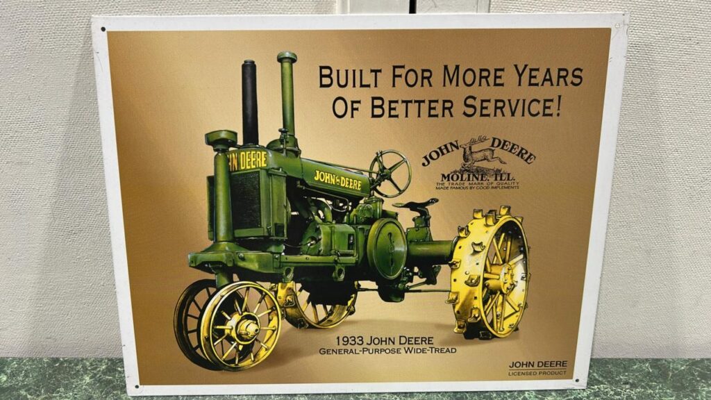 Metal square sign that reads Built for more years of Bteer Service - John Deere. The words are at the top right corner and the middle of the sign has a picture of a vintage green John Deere with yellow Steel Wheeled tractor