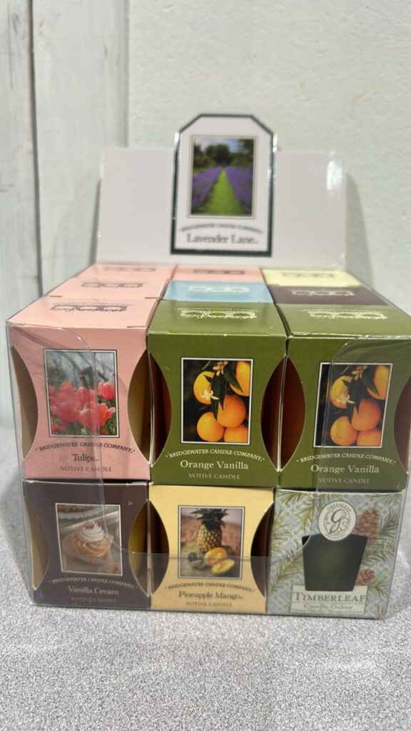Display box of 18 individually packaged votive candles with scentes that include vanilla cream, tulip, pineapple mango, and others