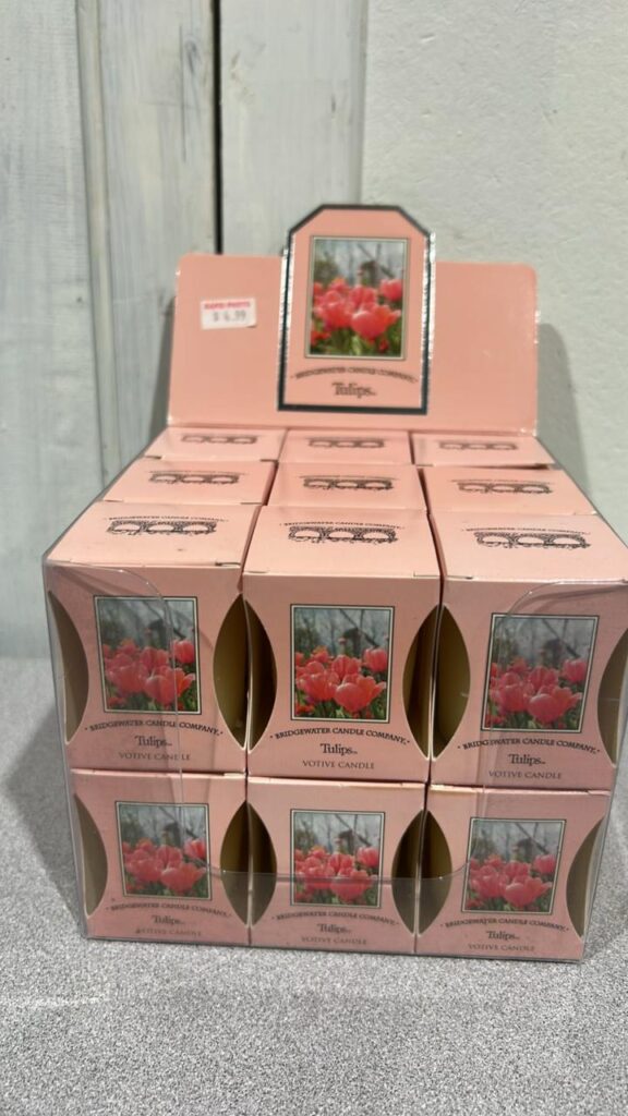Pink display box conatining 18 individually packaged Tulip Scented candle votives. Each box has a picture of a field of red tulips on it