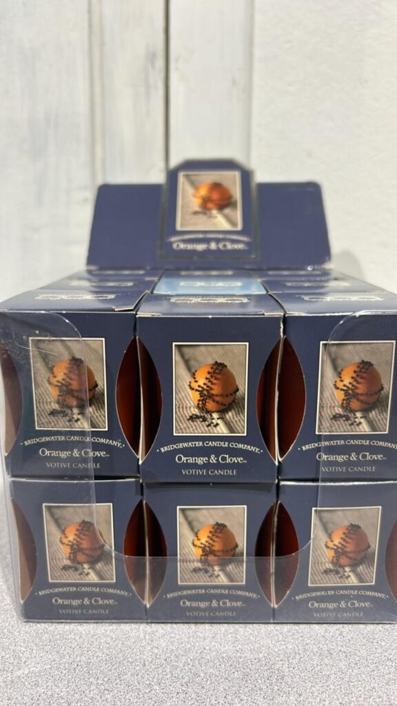 Blue display box containing individual blue boxes with a picture of an orange with a line of clove spices stuck into the orange