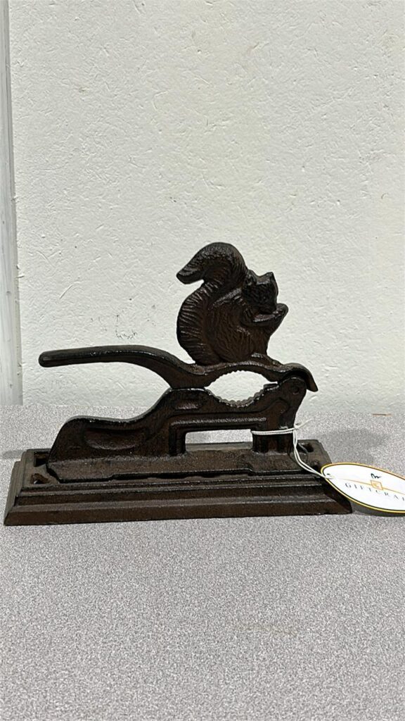 metal nutcracker attached to a metal base. there is a squirrel shape on nutcracker sitting directly above the area where you would place the nut