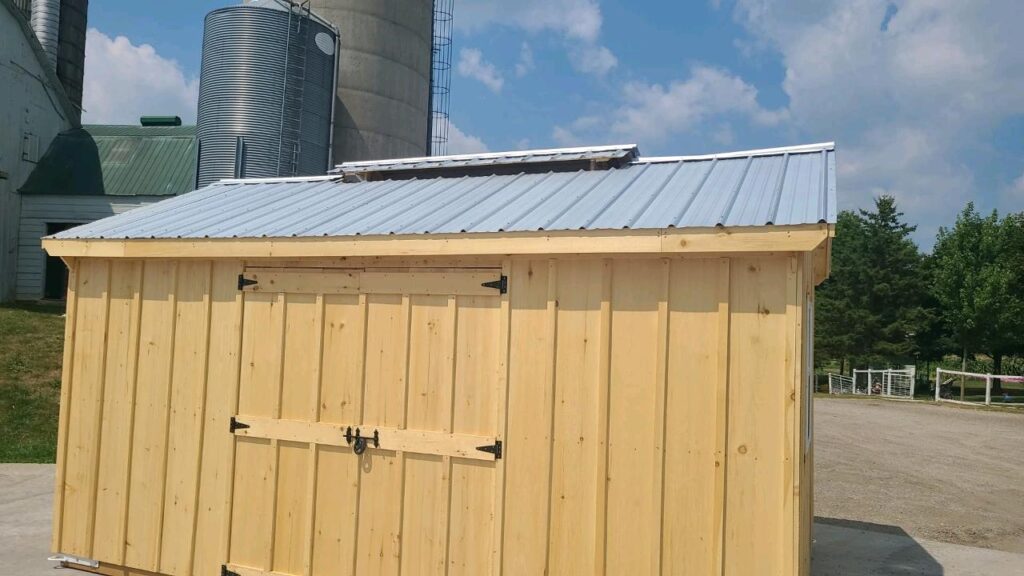 Back side of the 10ft x 16ft Sugar Shack - wooden structure with a metal roof and roof vents. Also shows a shutter covered opening just under the roof.